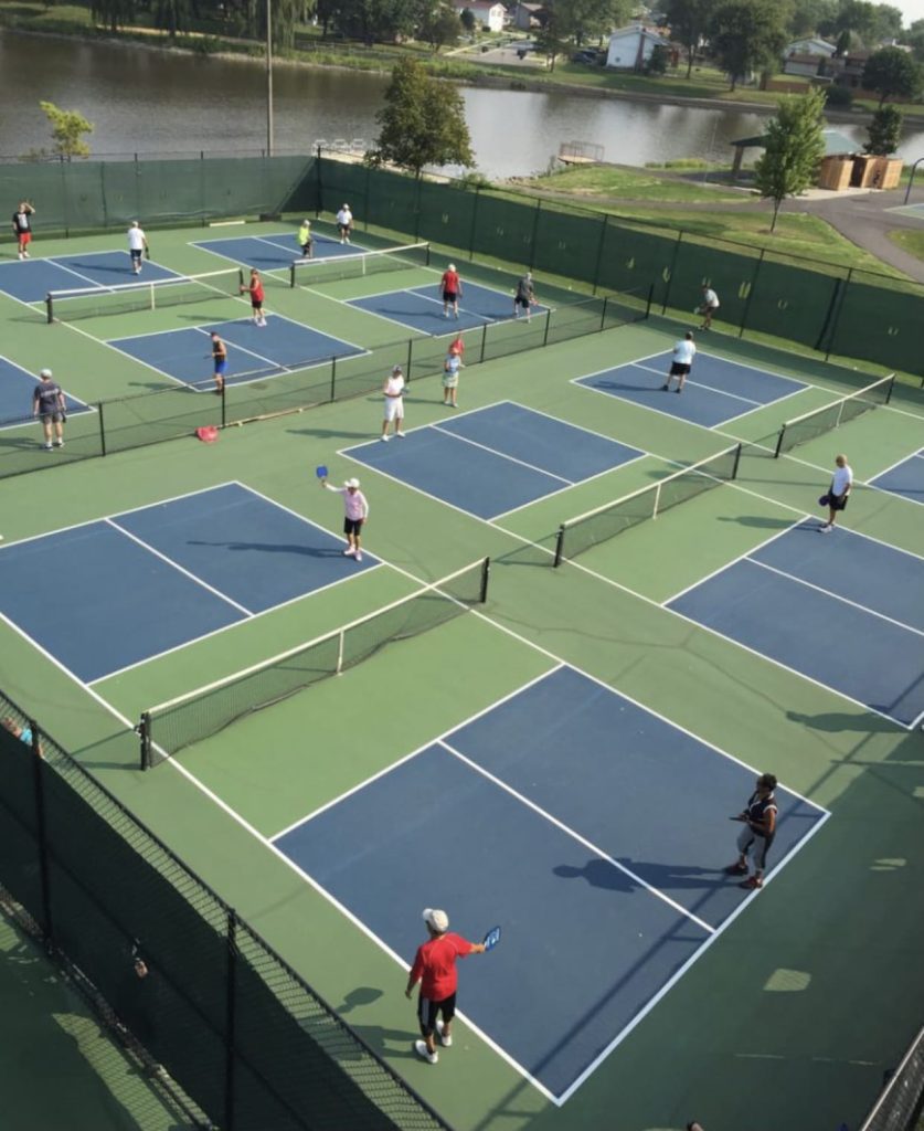 A group of outdoor enthusiasts playing tennis on a residential court.