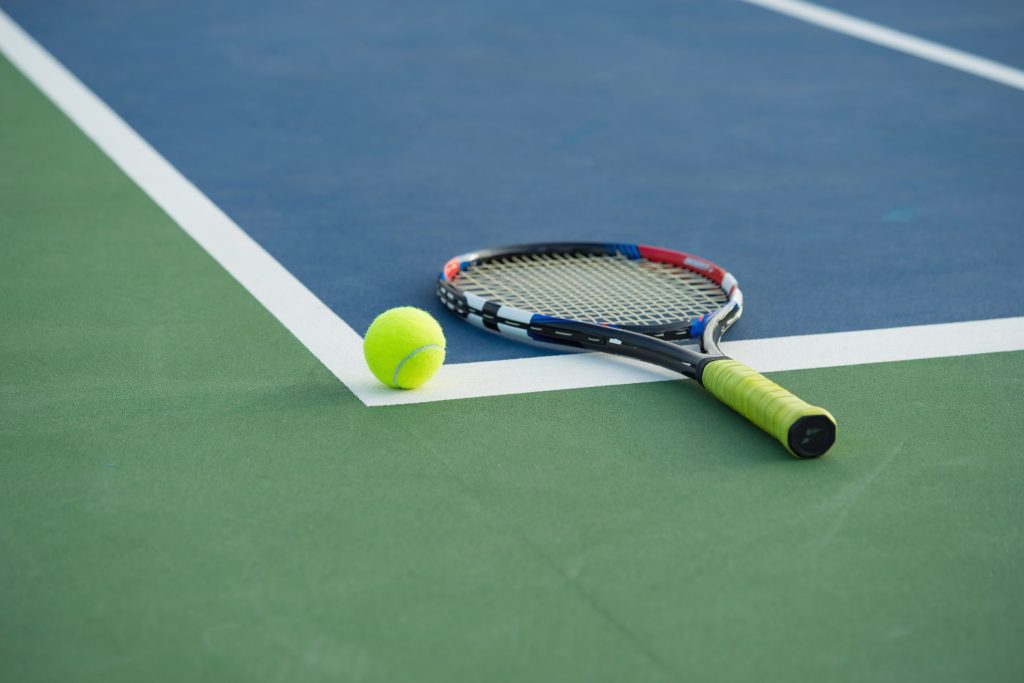A tennis racket and ball on a residential court.