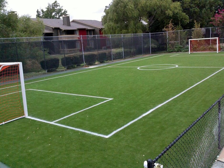 An outdoor artificial soccer field with a goal in the middle, ideal for residential homes.