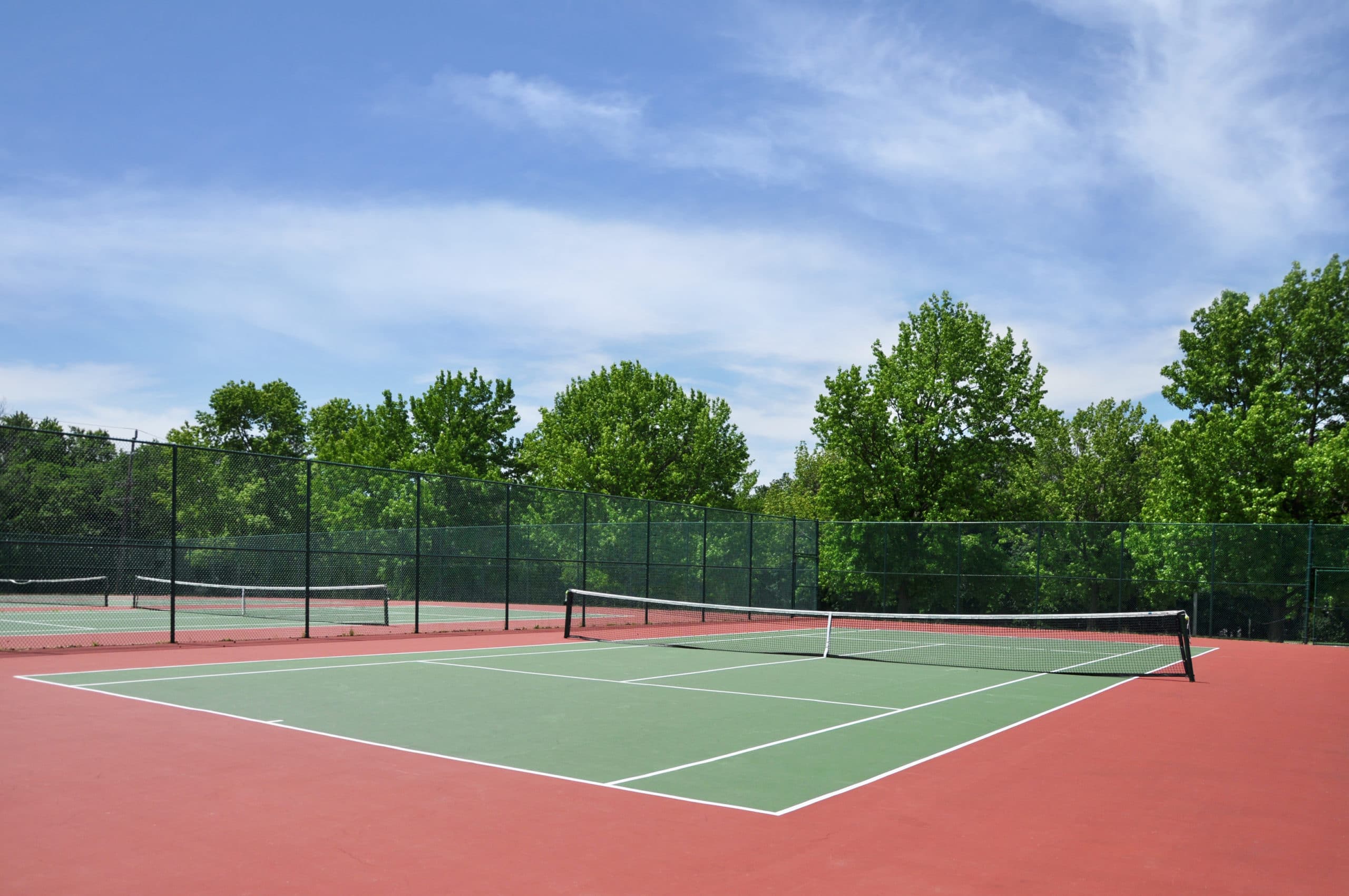 A residential tennis court surrounded by trees.