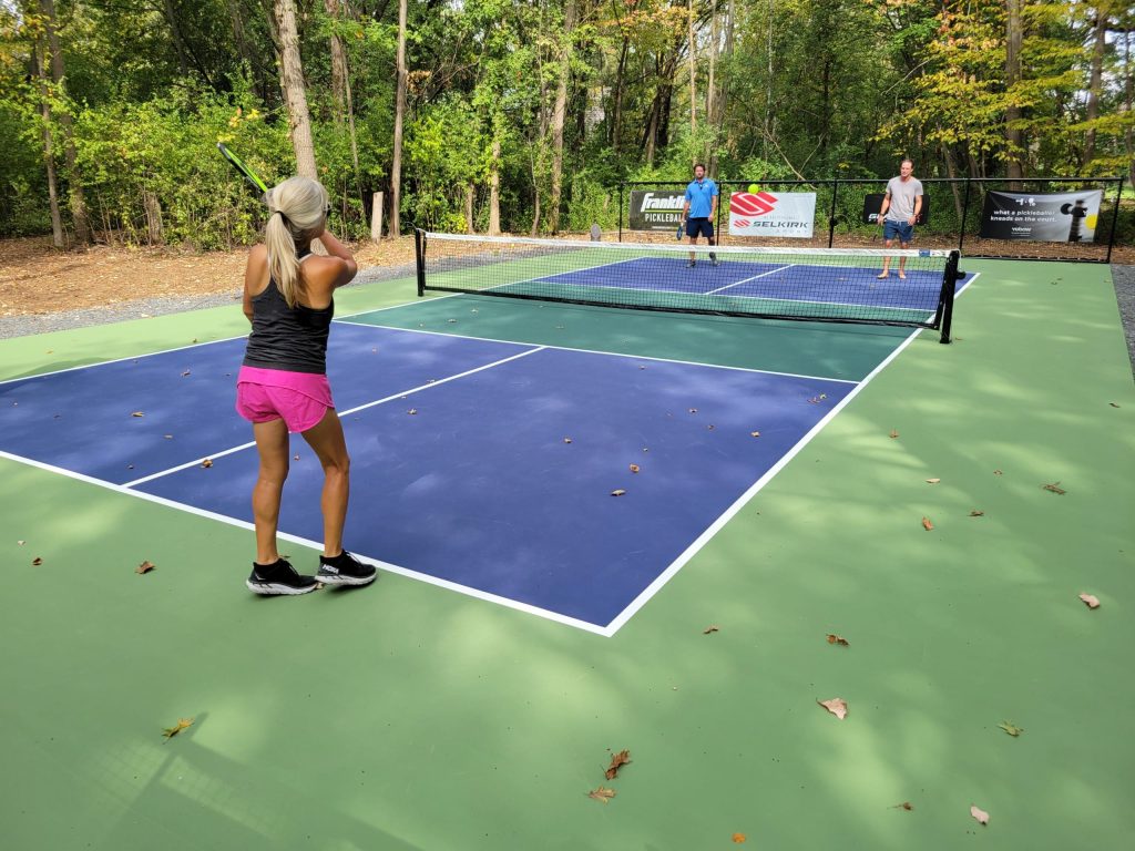 A group of people playing tennis on an outdoor court.
