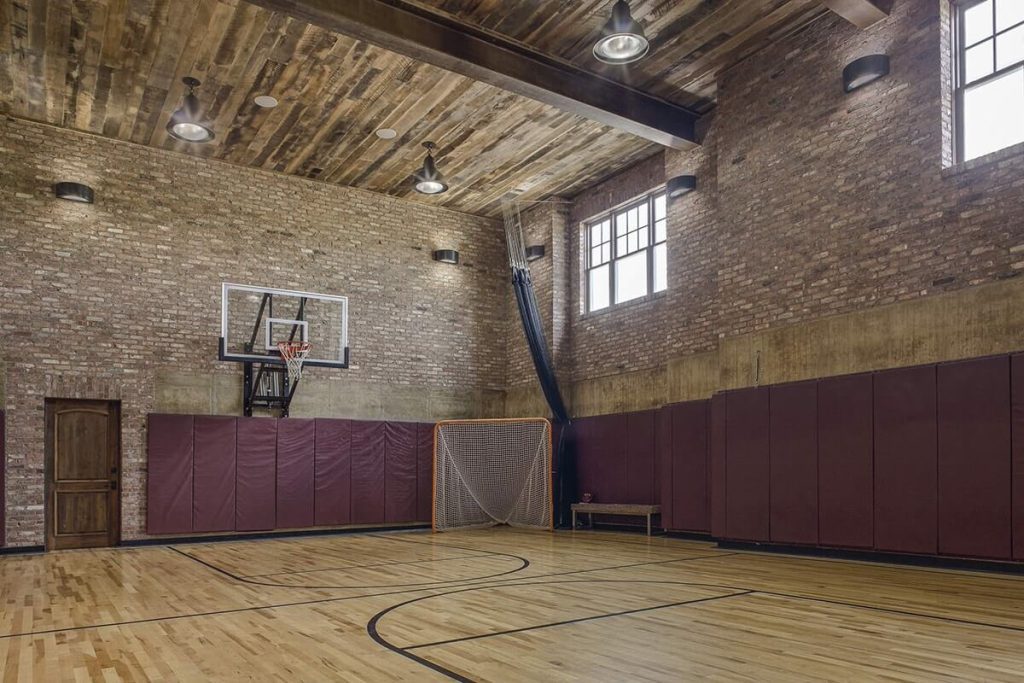 A residential basketball court with brick walls and a basketball hoop.