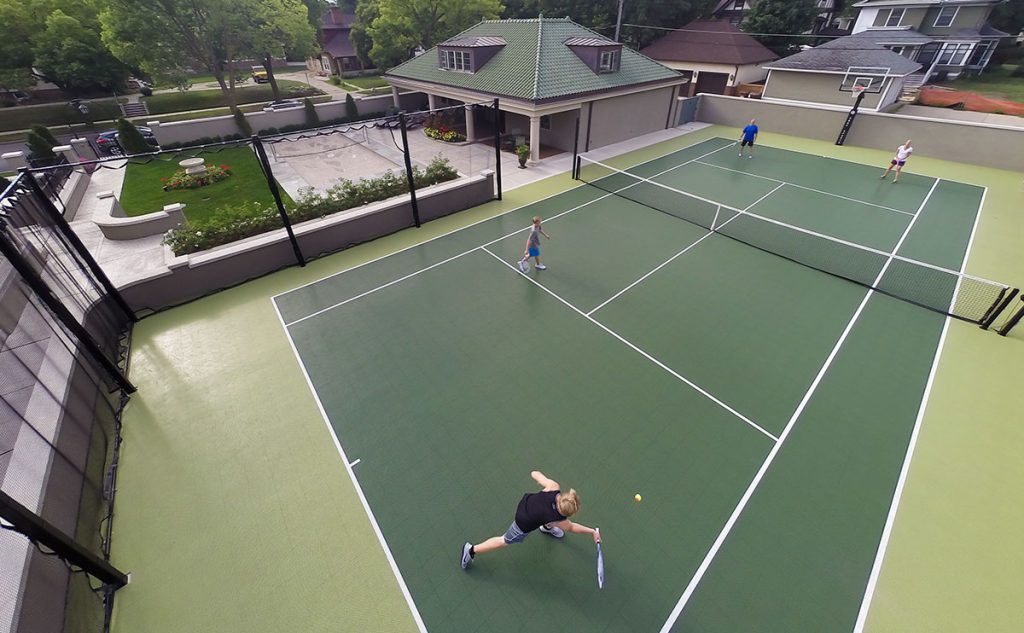 An aerial view of a residential tennis court with people playing on it.