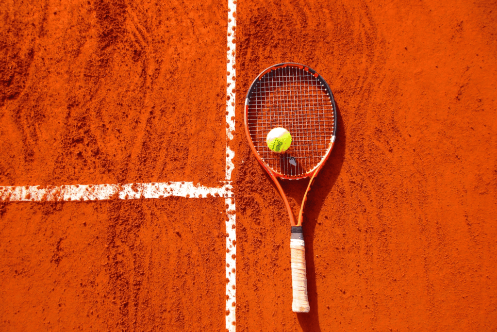 A tennis racket on a clay court.