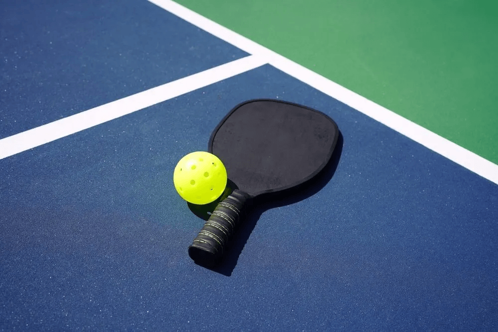 A tennis racket and ball on a tennis court with Court Surface Coating.
